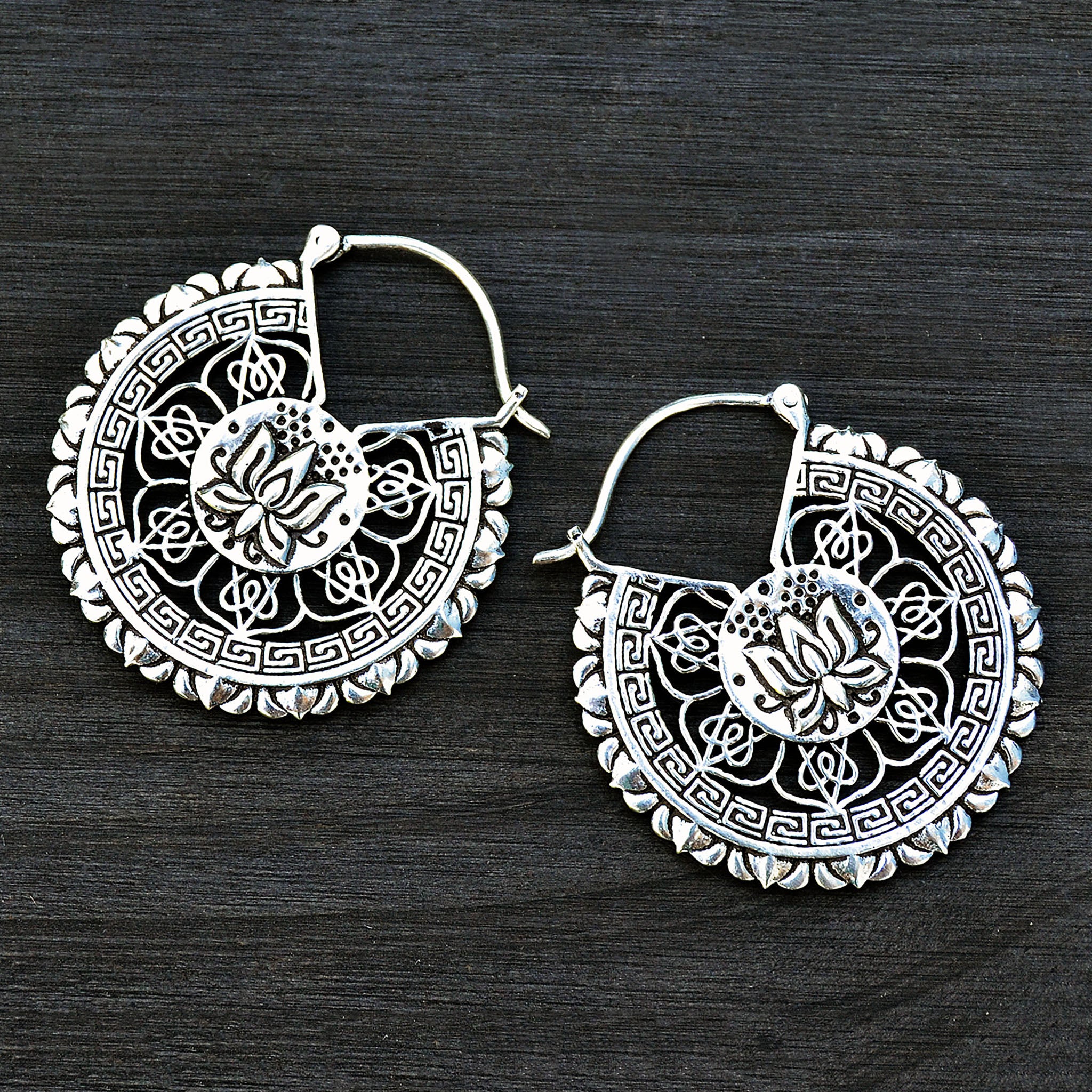 Silver lotus mandala hoop earrings on black background