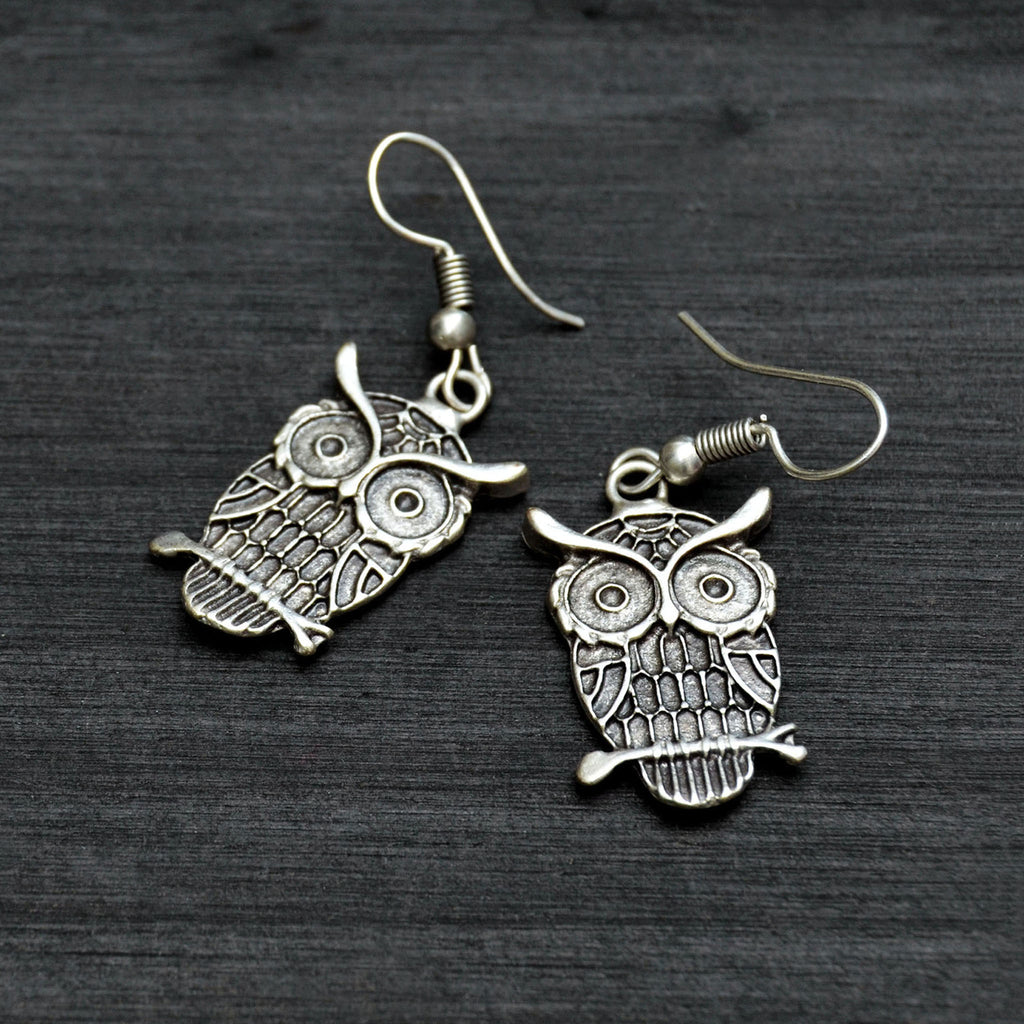 Silver dangly owl earrings on black background