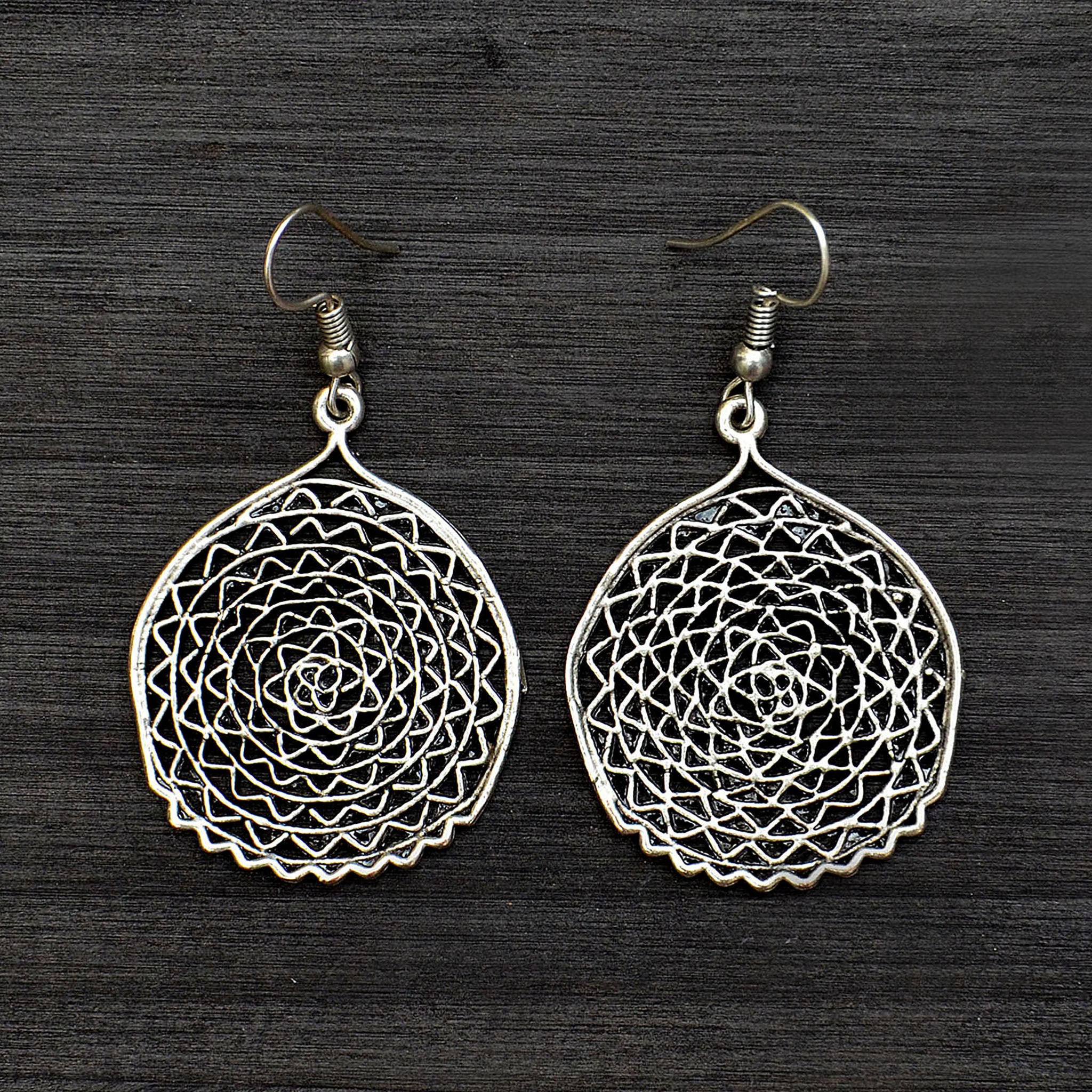 Silver filigree disc hanging earrings on gray background