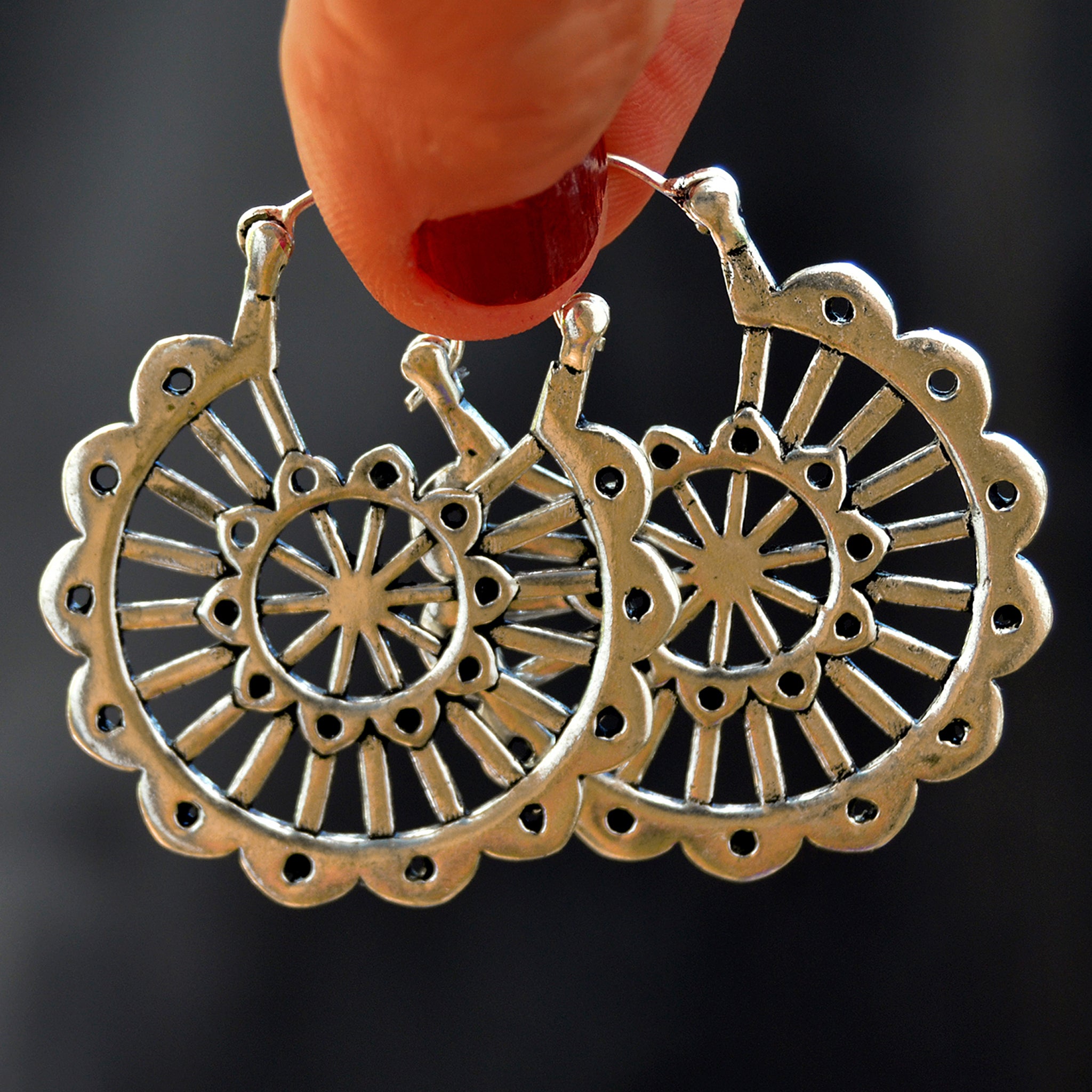 Silver carved mandala earrings in black background