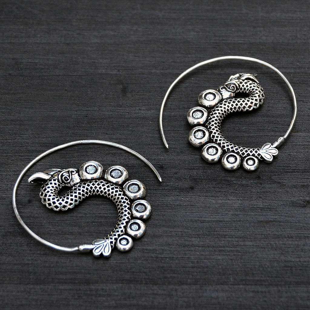 Silver tribal spiral dagon earrings on black background