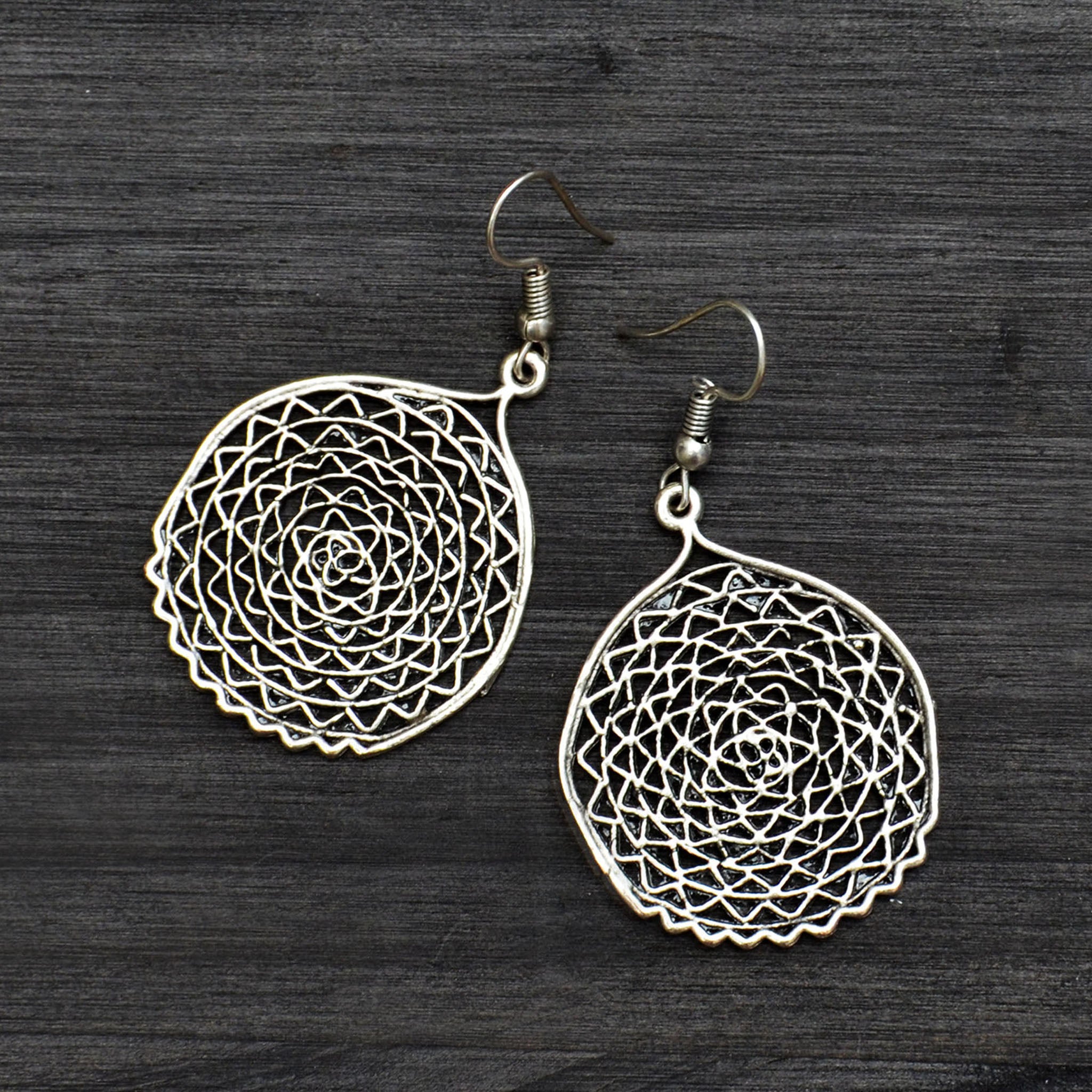 Silver filigree round dangle earrings on gray background