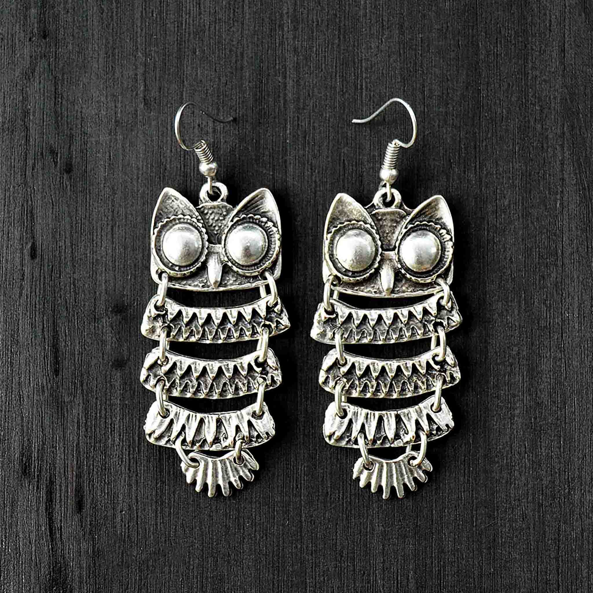 Silver dangle owl earrings on black background
