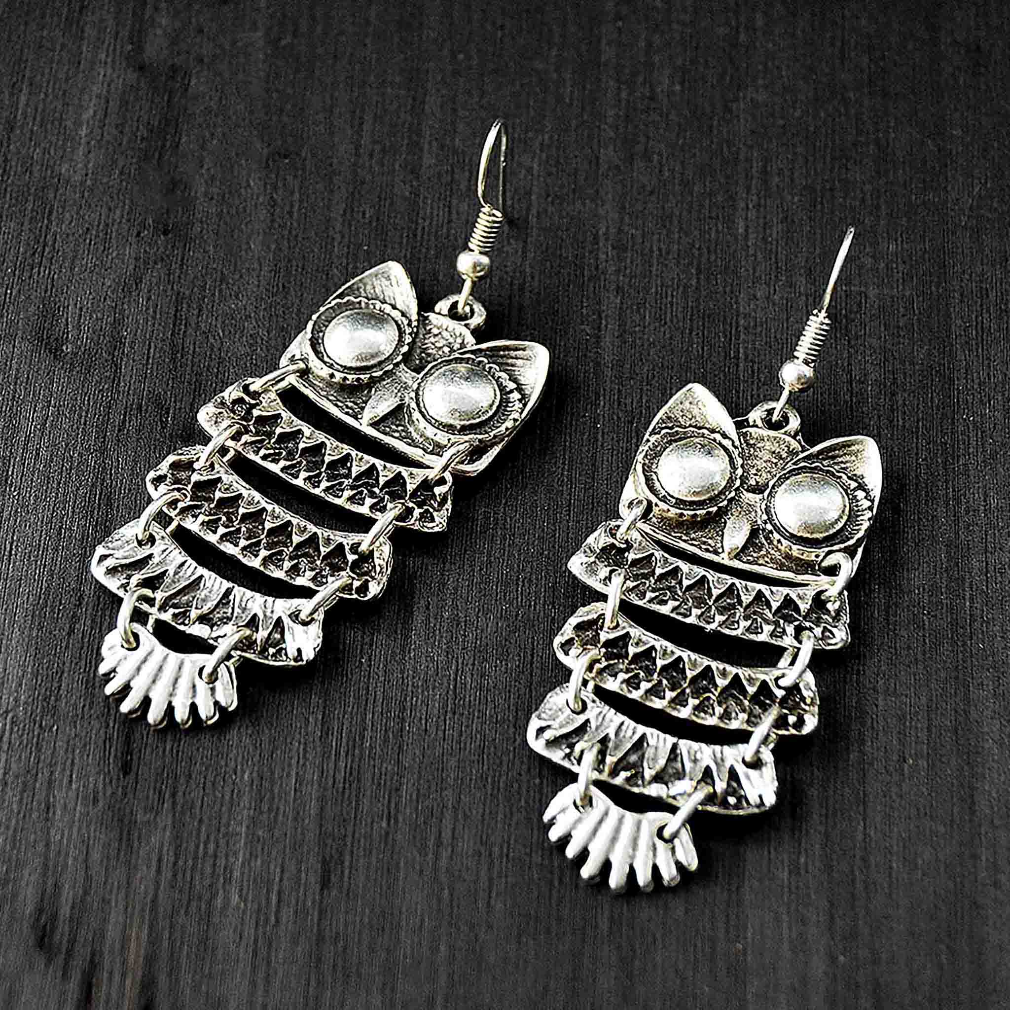 Silver long owl earrings on black background