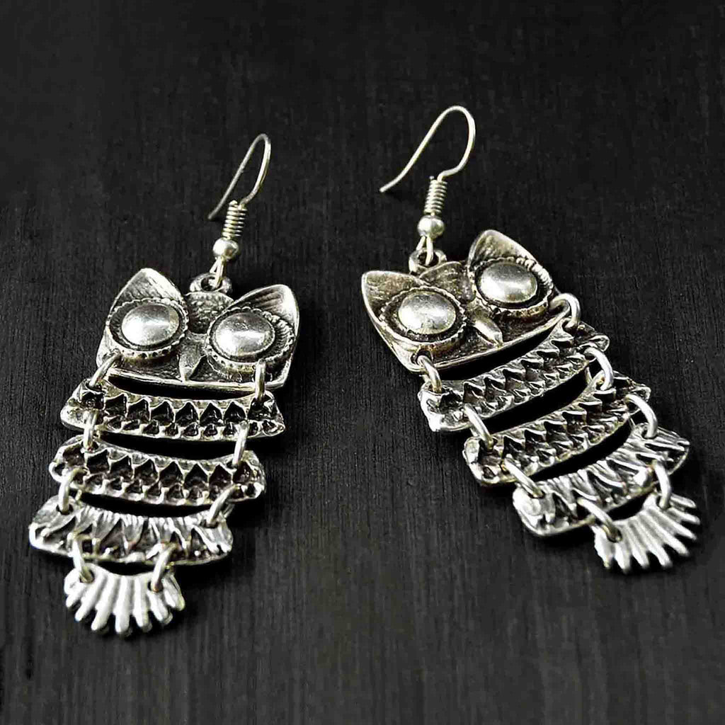 Silver owl earrings on black background
