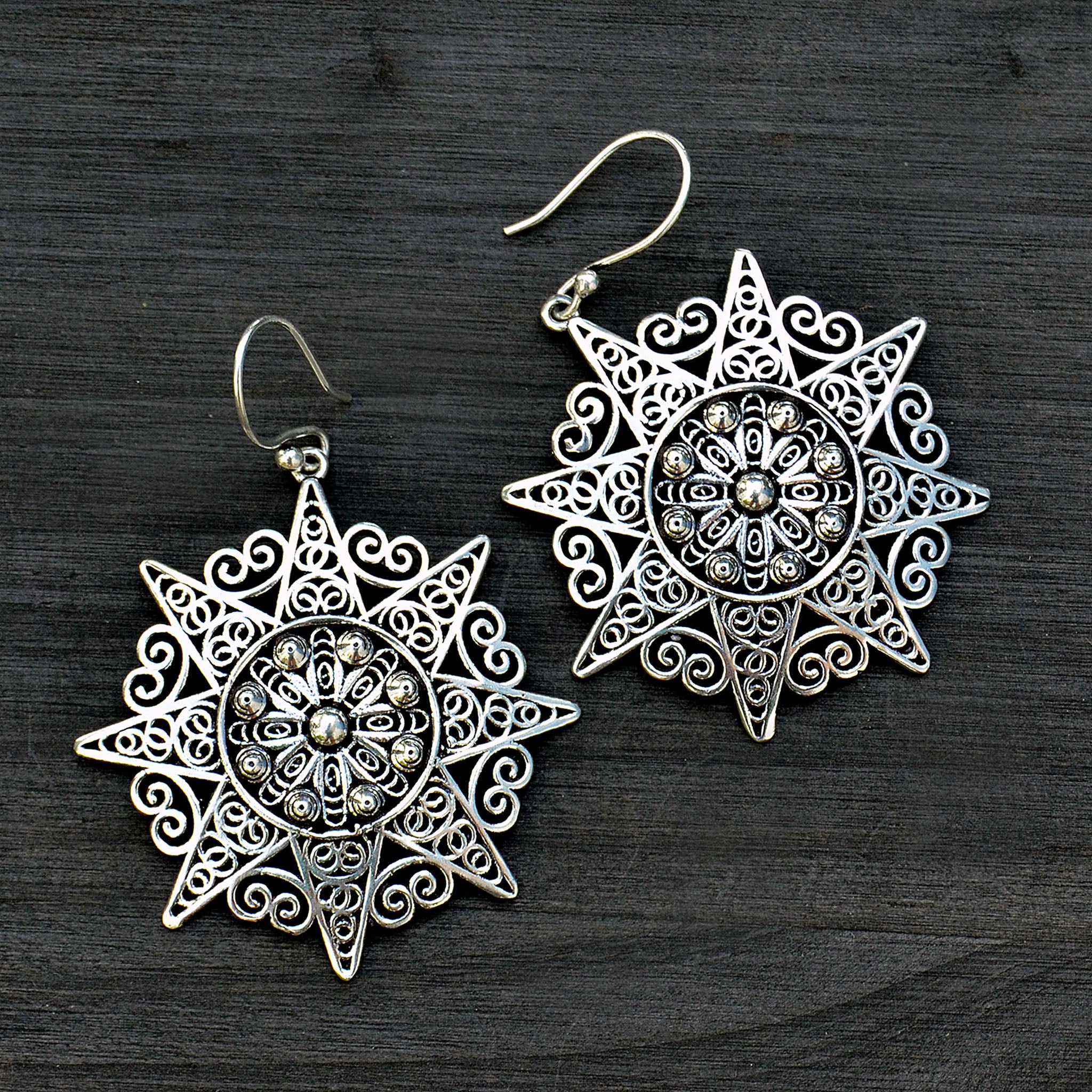 Indian silver filigree mandala earrings on black background