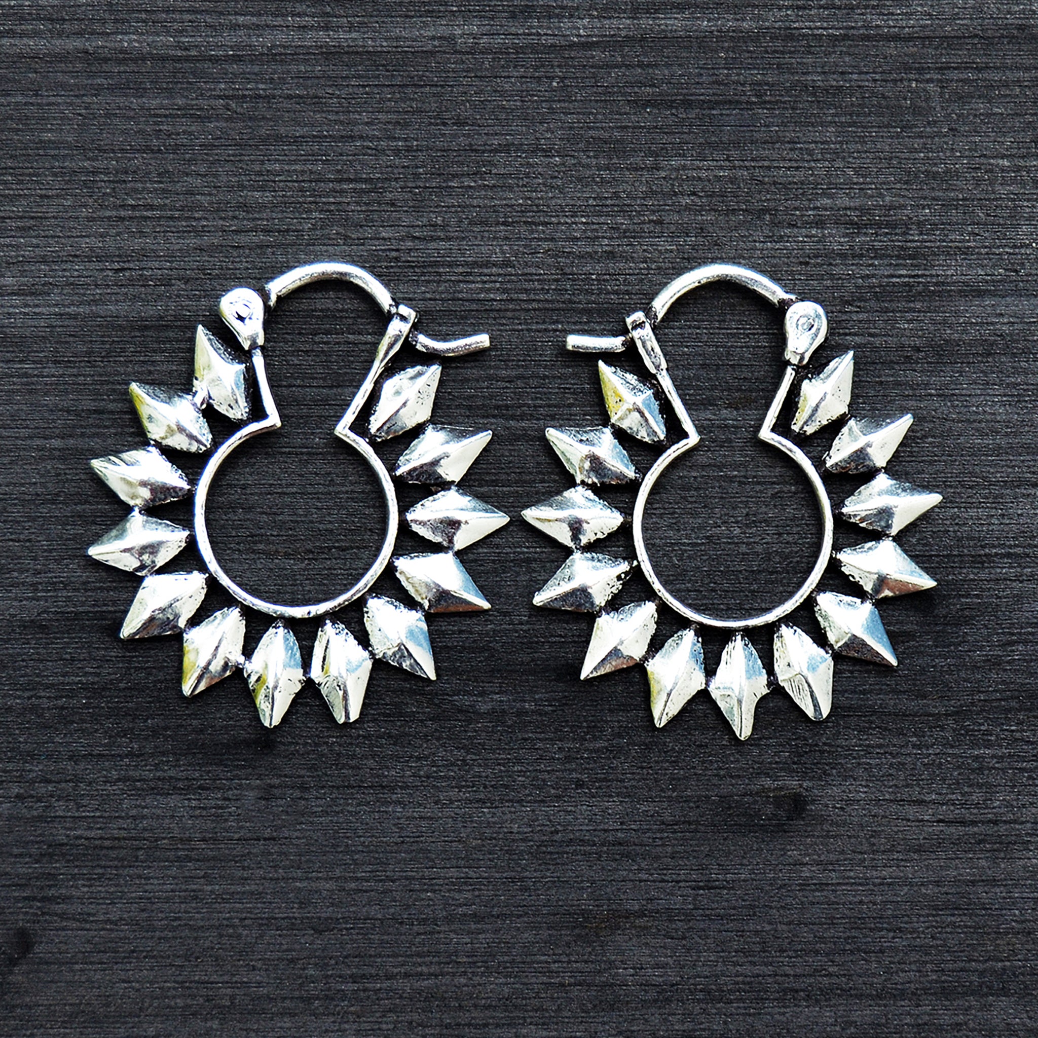 Silver sun hoop earrings on black background