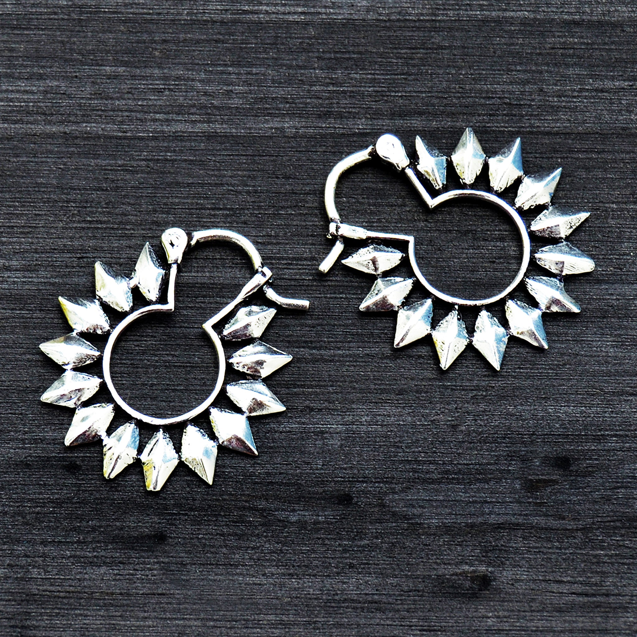 Silver tribal sun hoop earrings on black background
