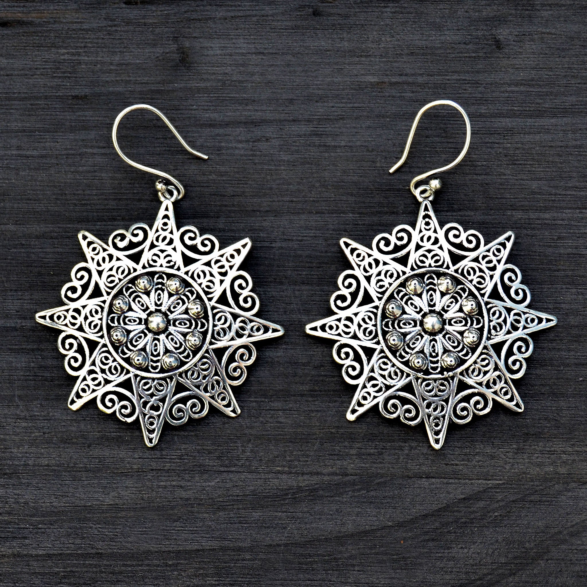 Ethnic silver filigree mandala earrings on black background