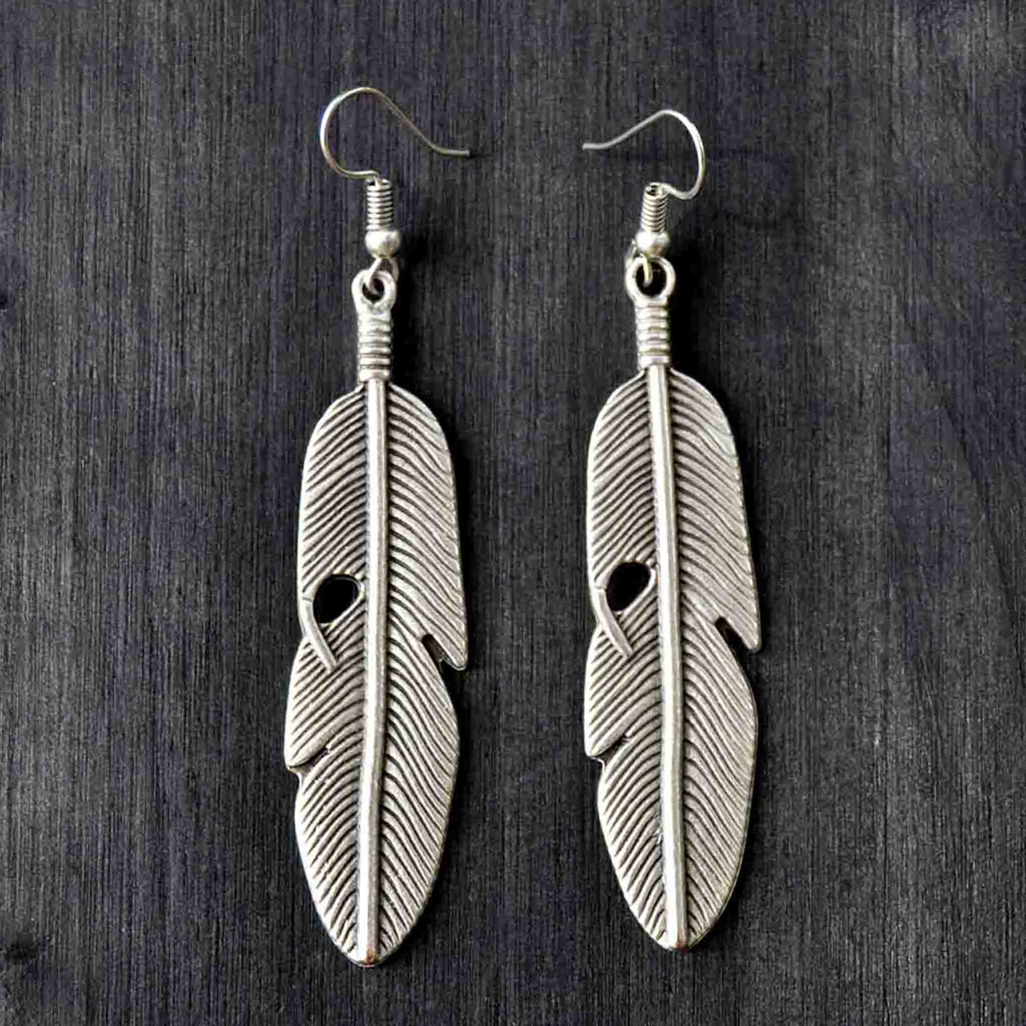 Long silver dangle feather earrings on gray background
