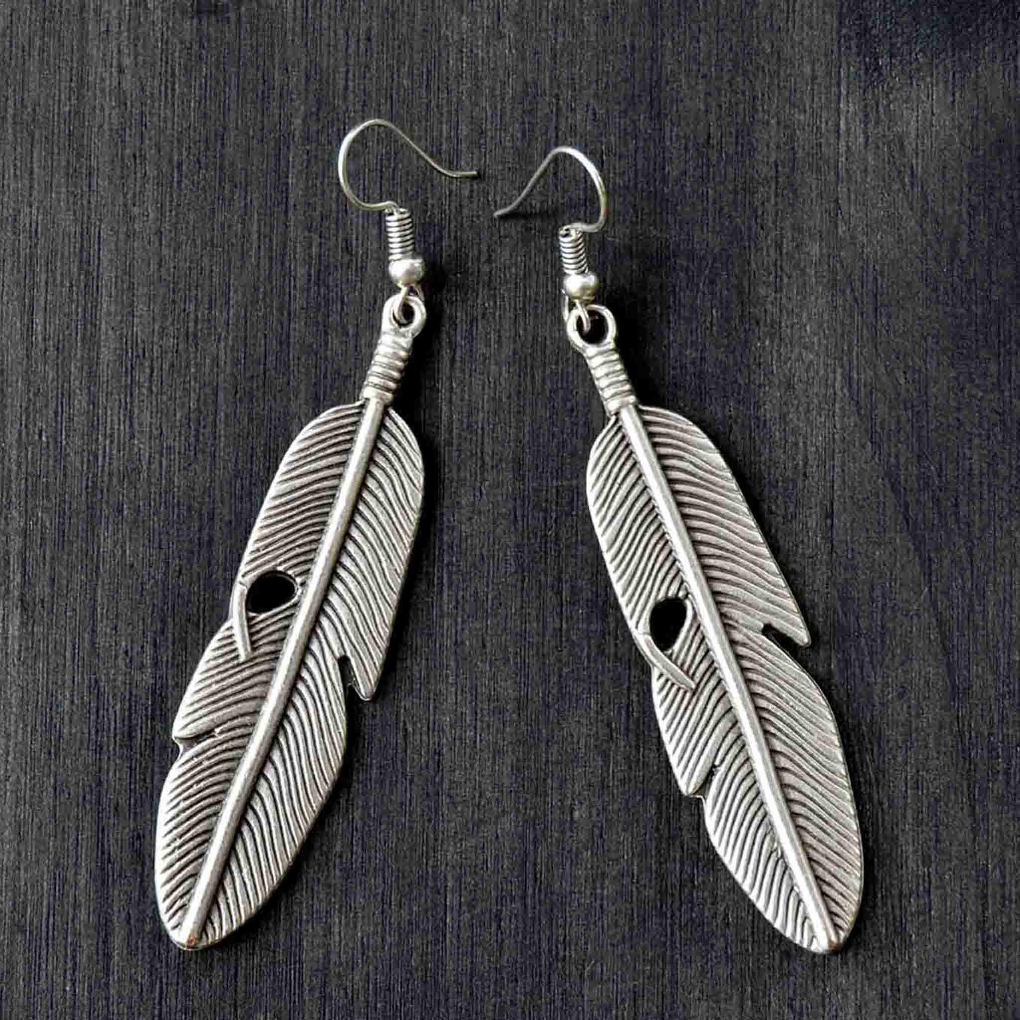 Long silver feather dangly earrings on gray background