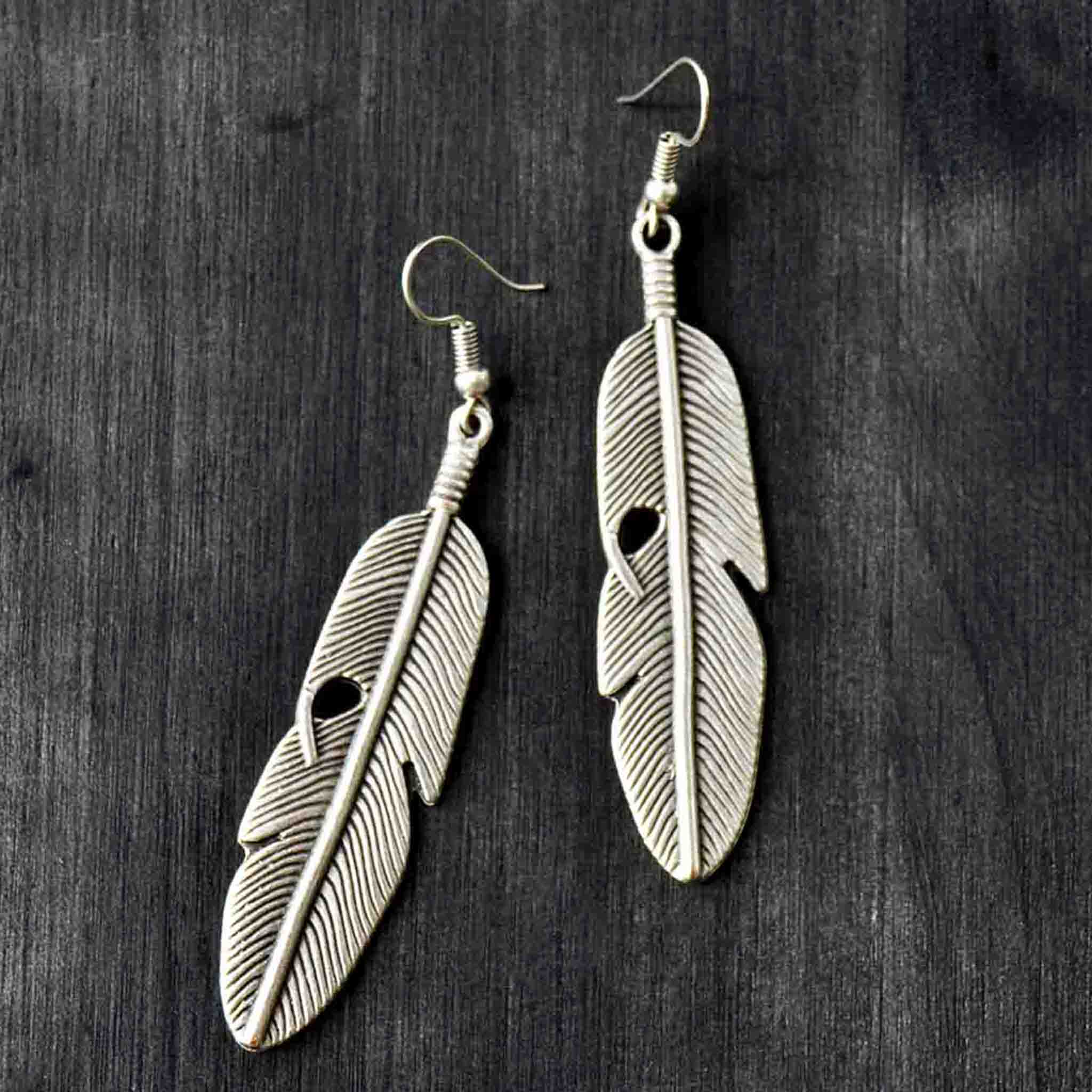 Long silver feather drop earrings on gray background