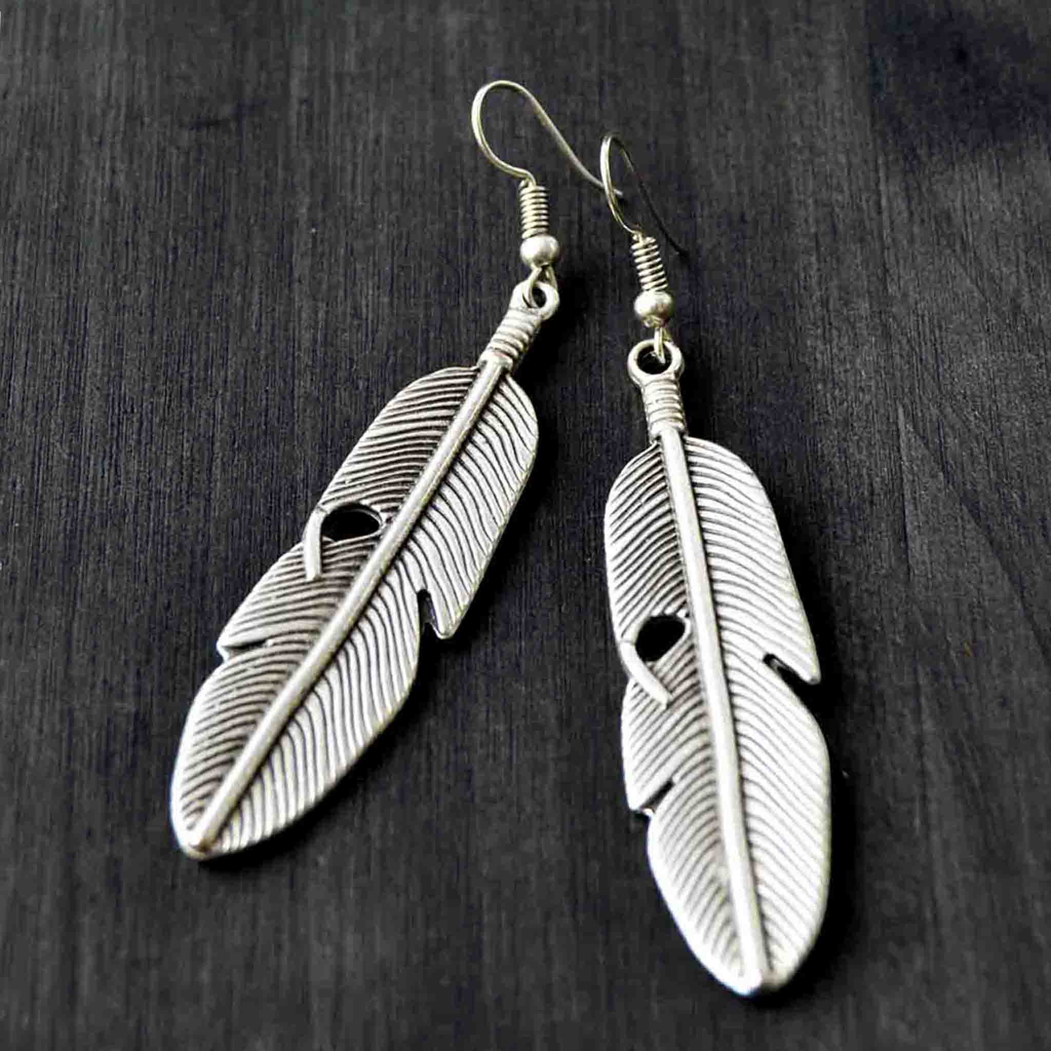 Silver feather  dangle earrings on gray background