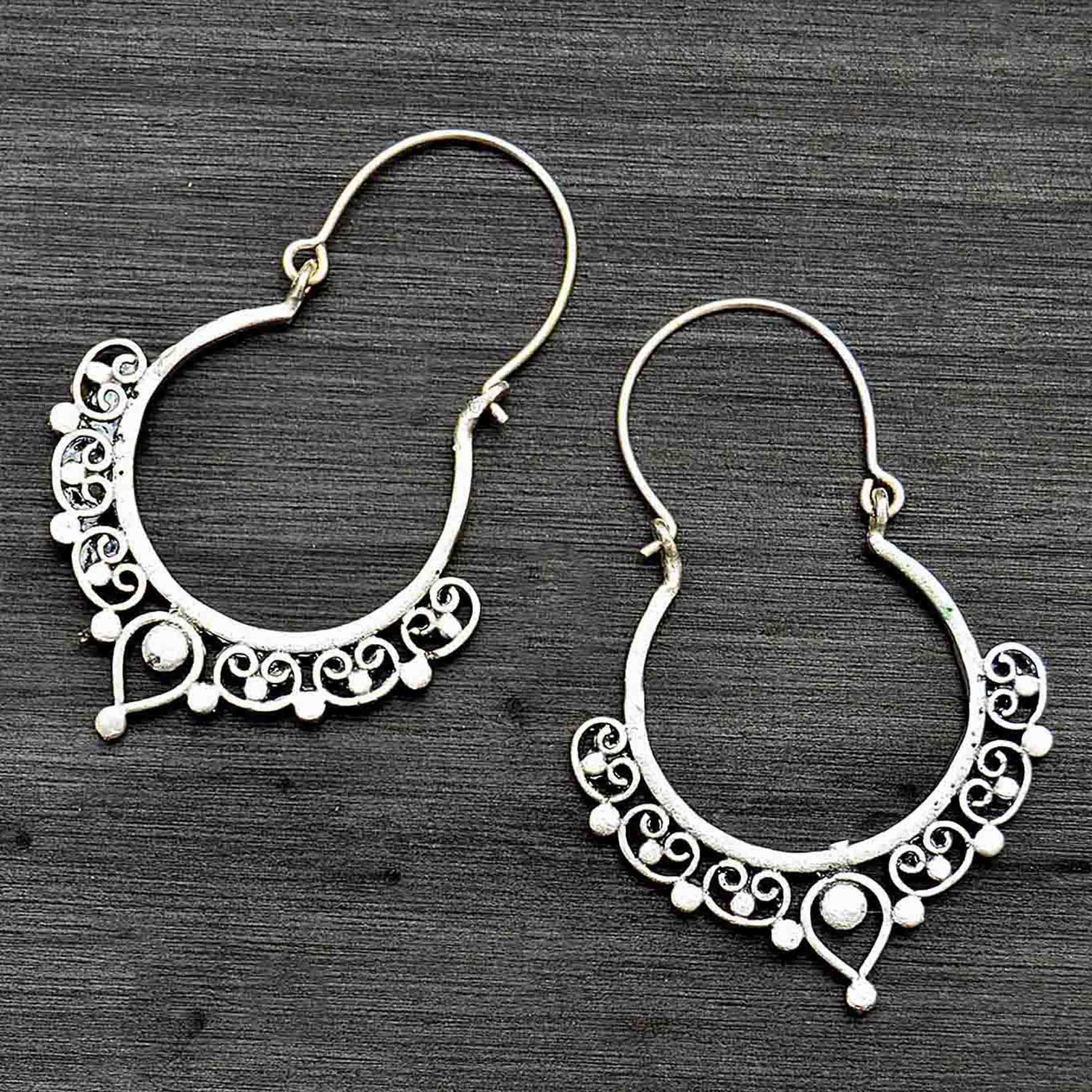 Silver ethnic indian hoop earrings on black background