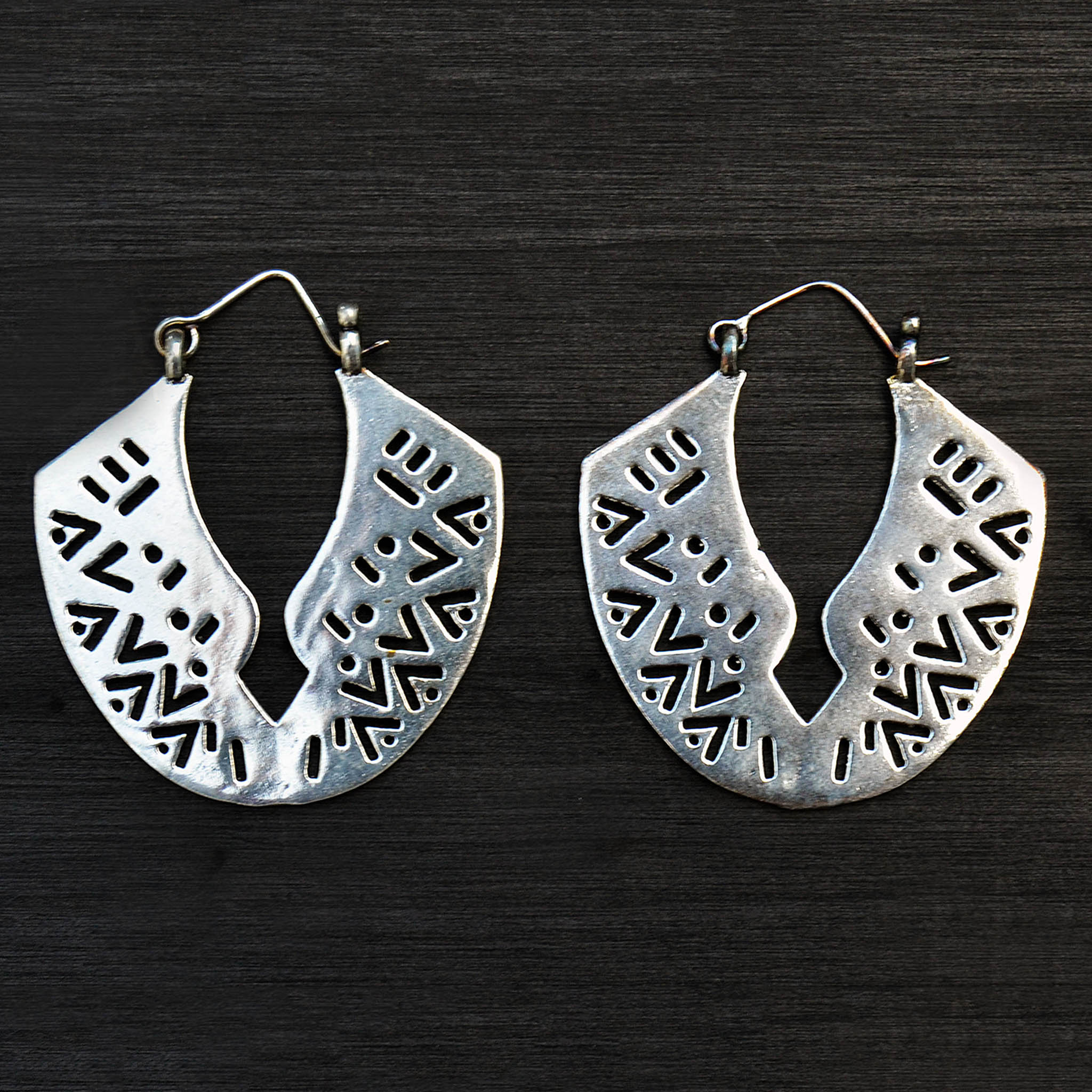 African silver carved earrings on black background