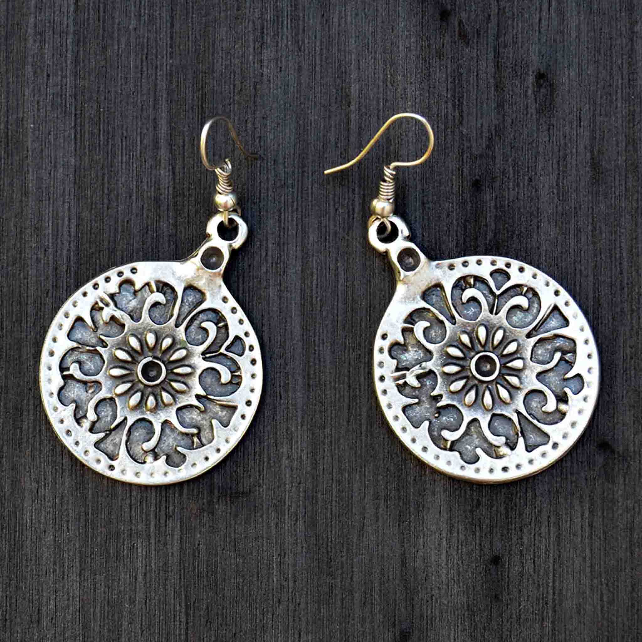 Silver celtic mandala dangly earrings on black background