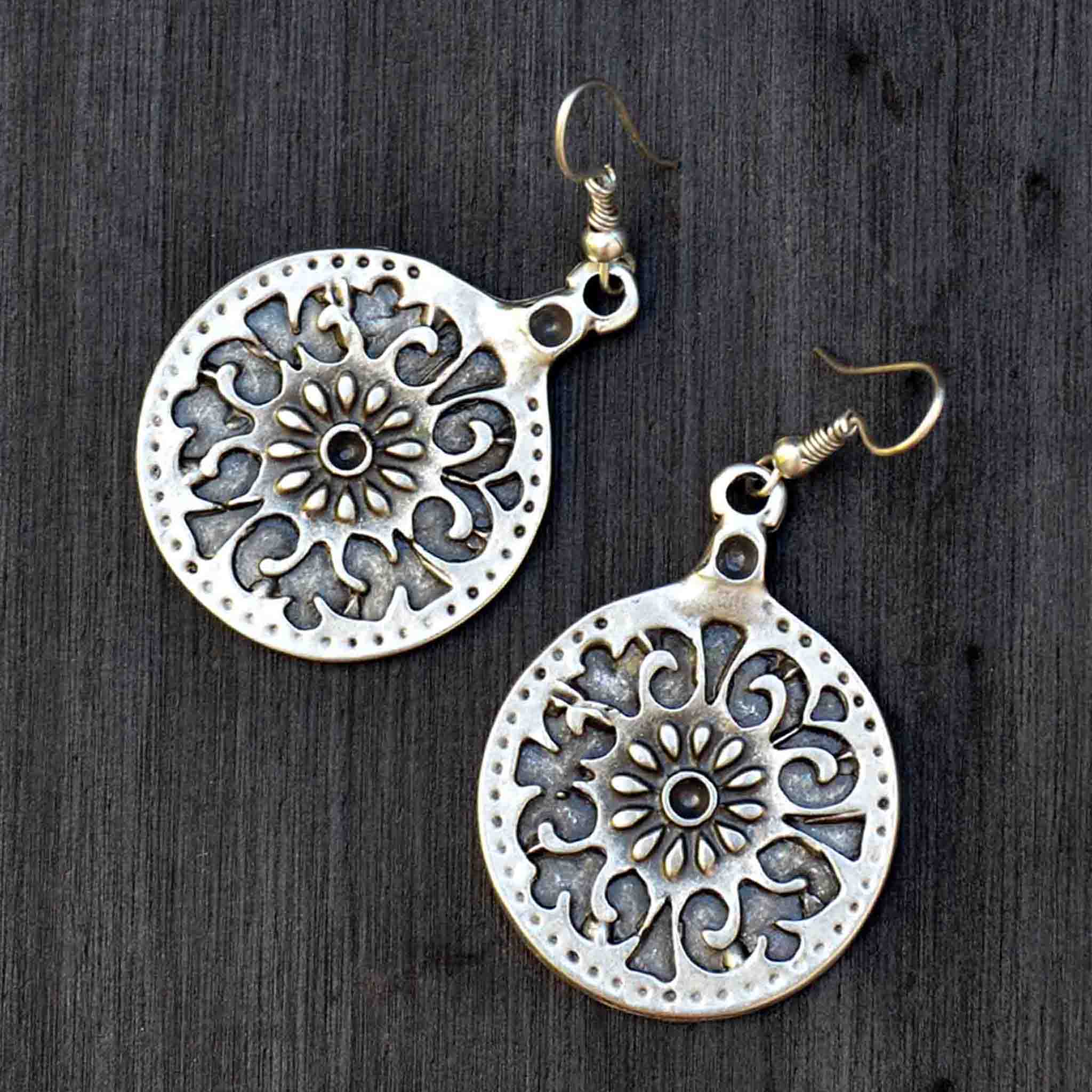 Silver celtic mandala dangly earrings on black background