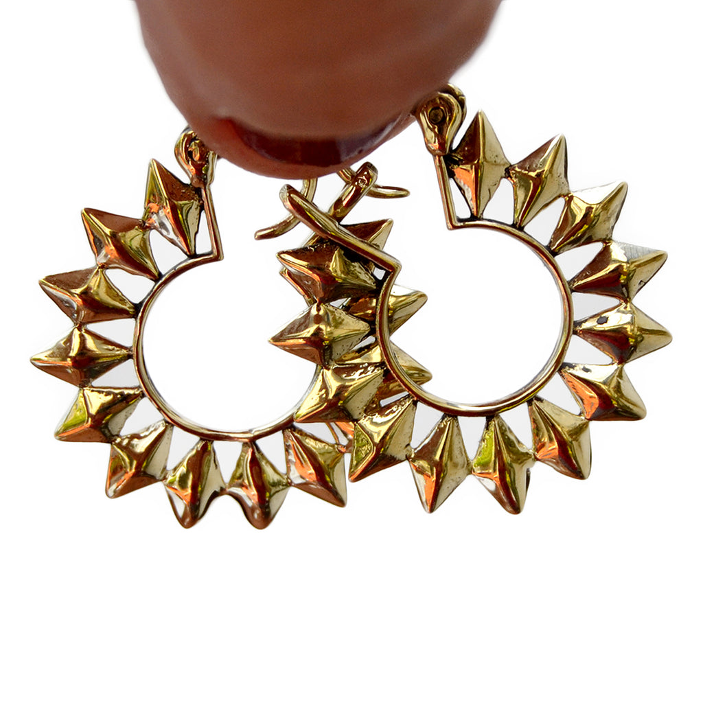 Small gold sun hoop earrings hanging on finger