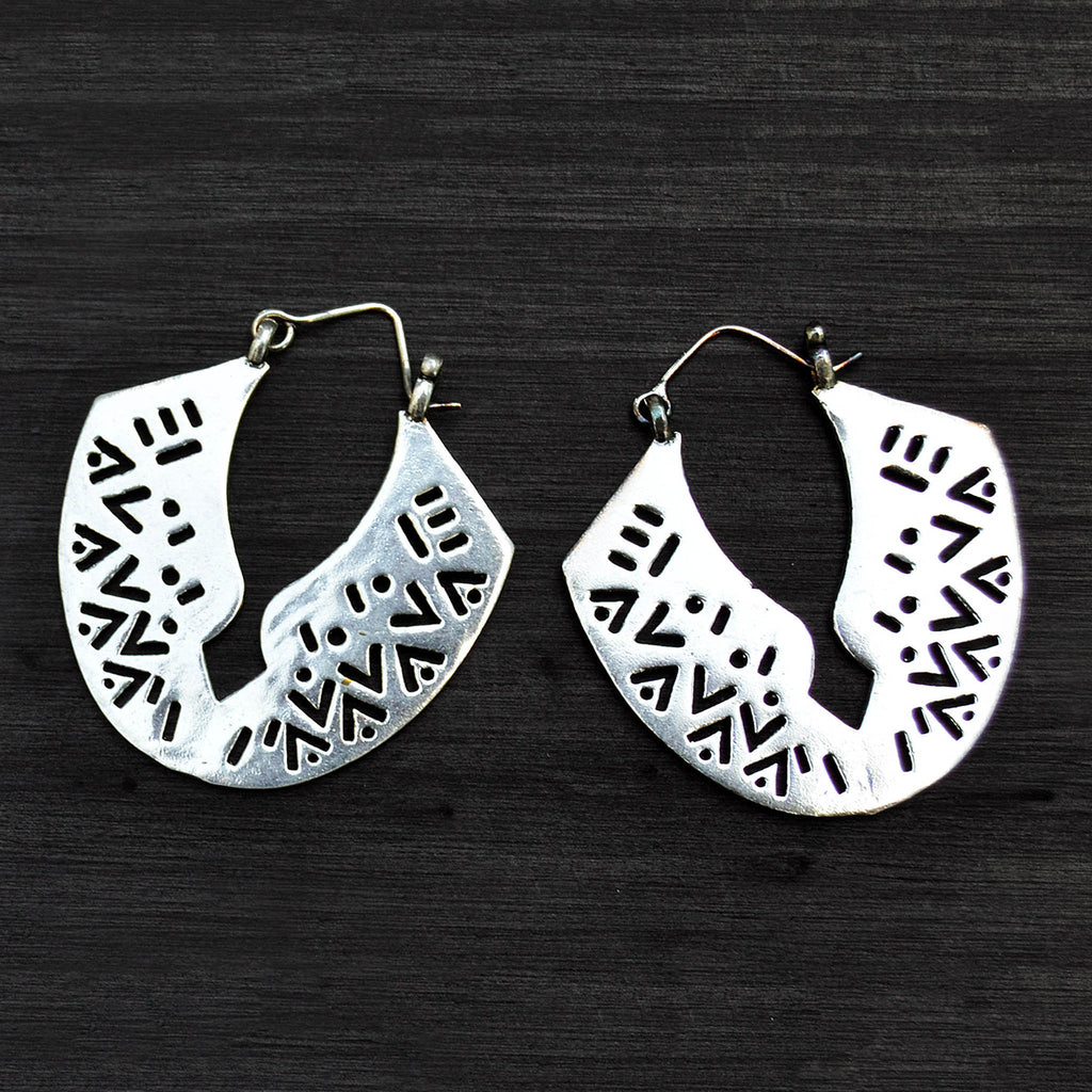 Large tribal silver carved earrings on black background