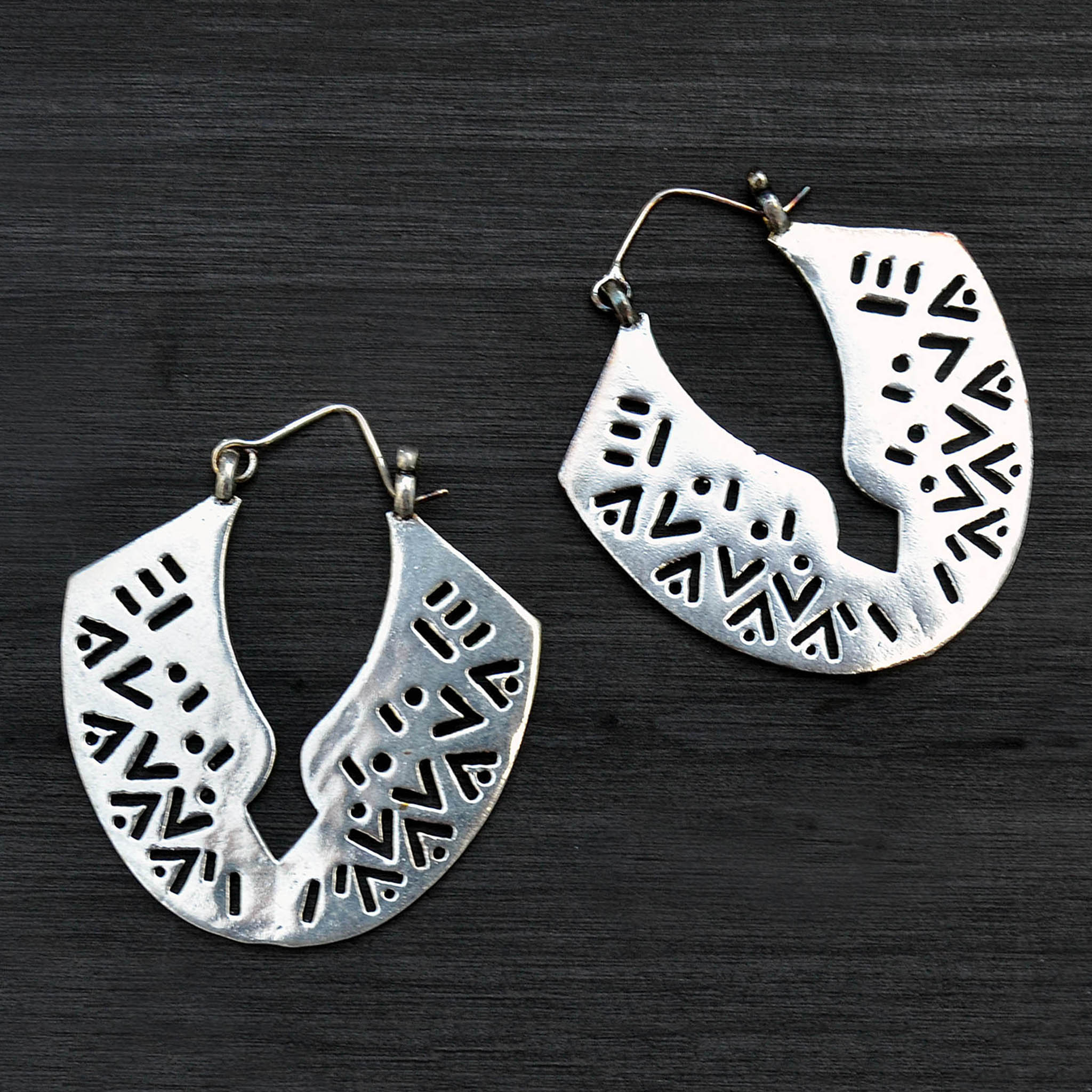Large ethnic silver carved earrings on black background