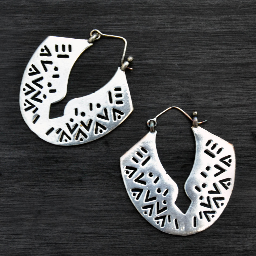 Large african tribal silver carved earrings on black background