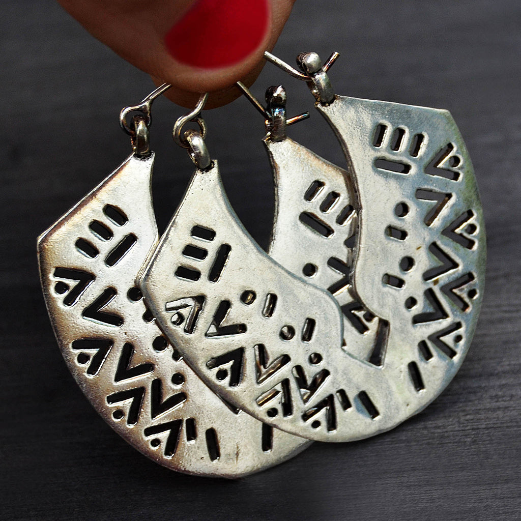 Large tribal african carved silver earrings on black background