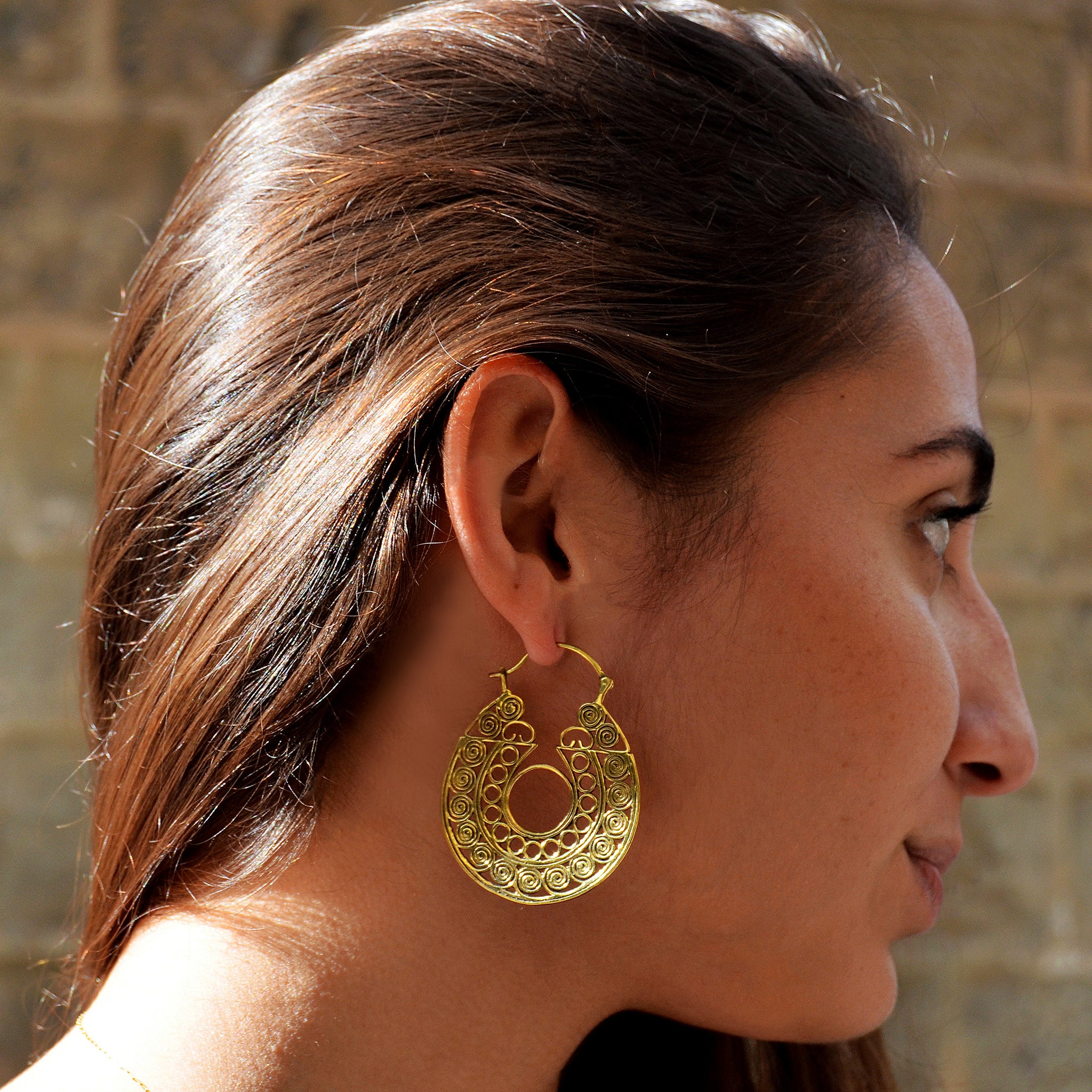 Young woman with long brown hair wearing brass indian  filigree hoop earrings