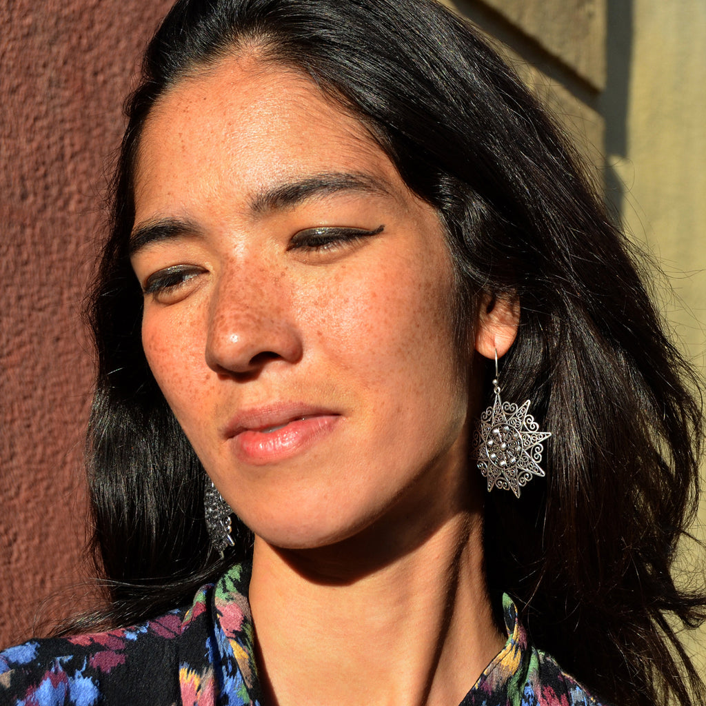 Young woman with black long hair wearing filigree mandala earrings