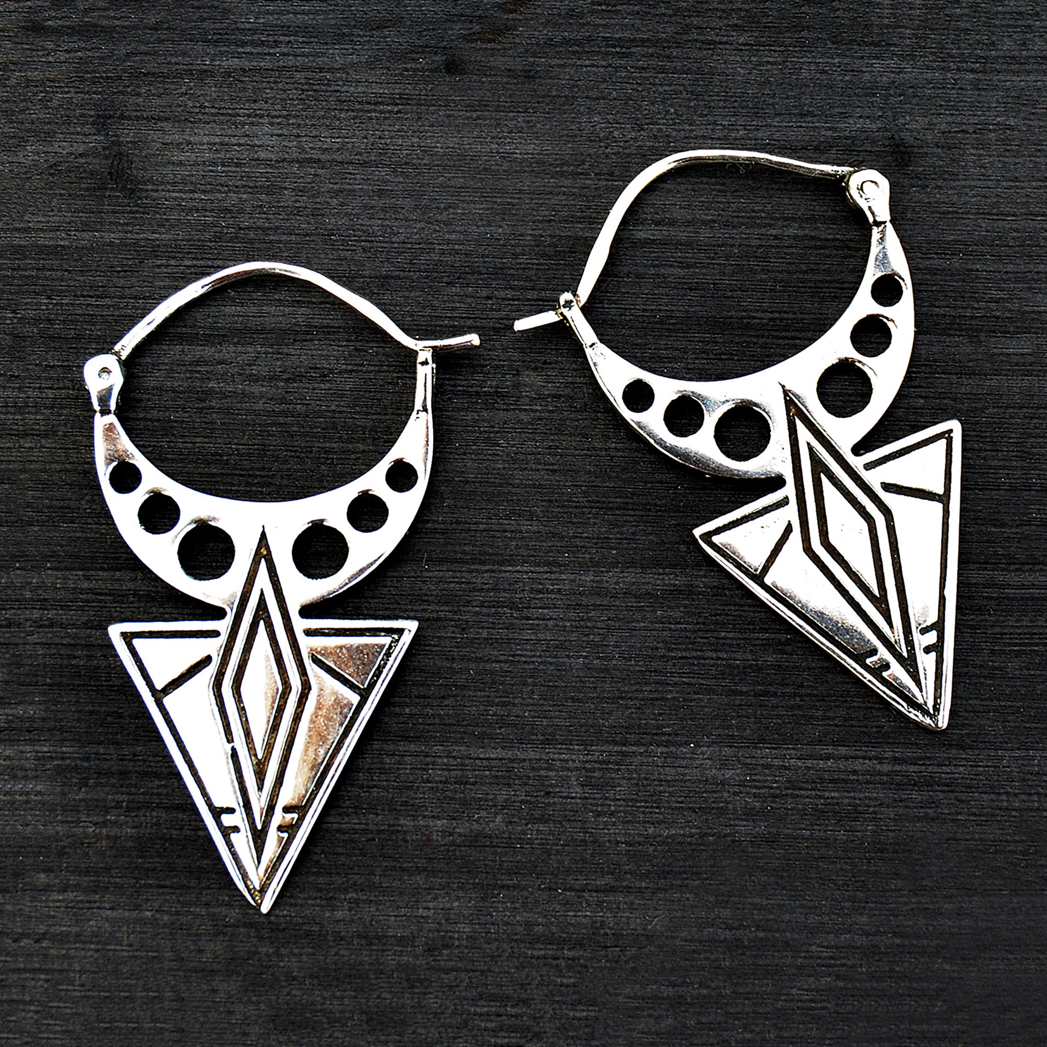 Silver geometric aztec earrings on black background