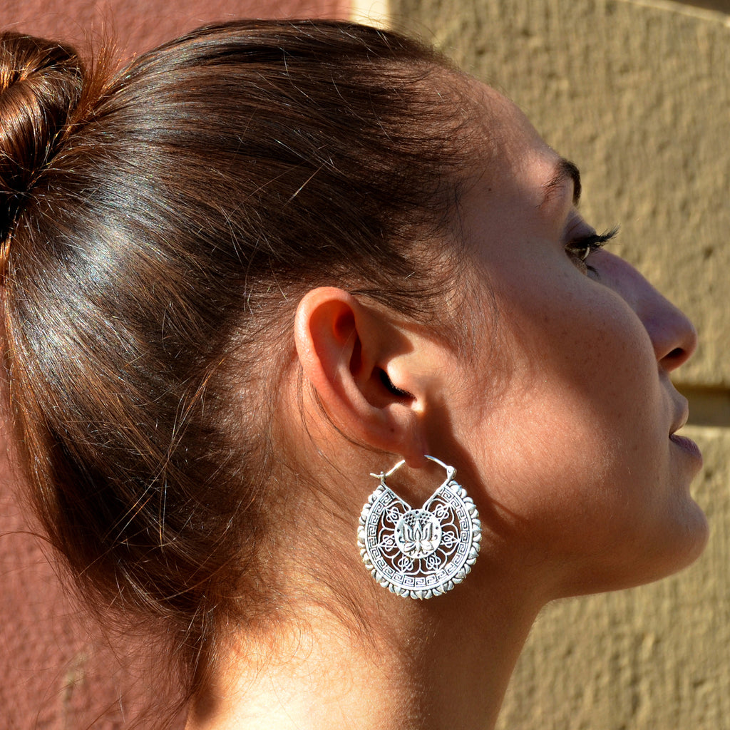 Young woman with bun wearing silver lotus mandala earrings