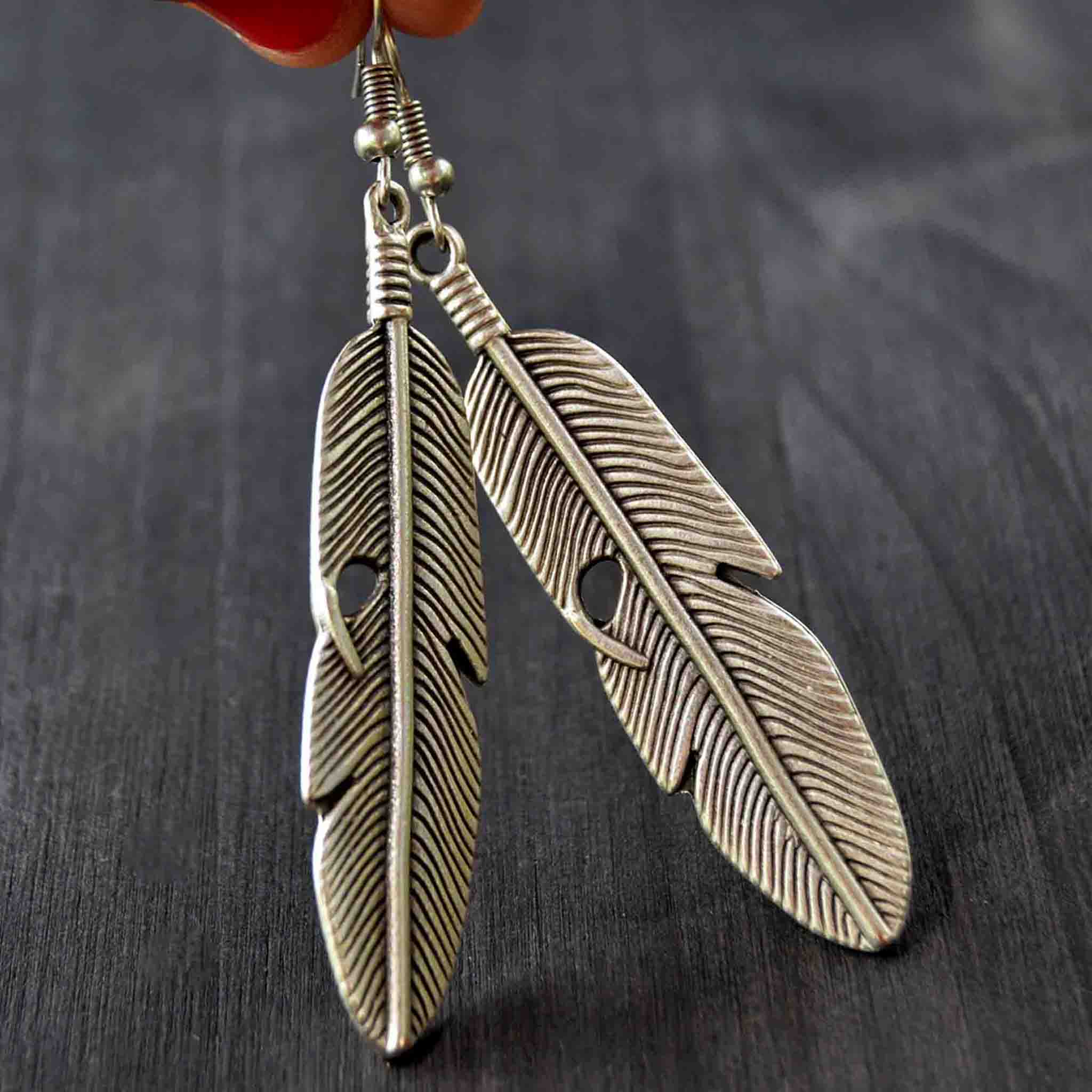 Long silver feather earrings on gray background