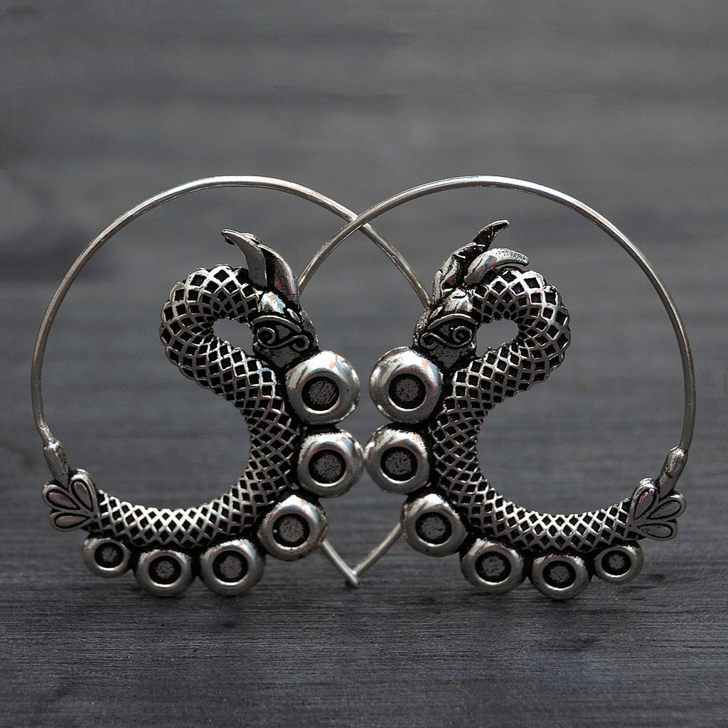 Intricate spiral silver dagon earrings on black background