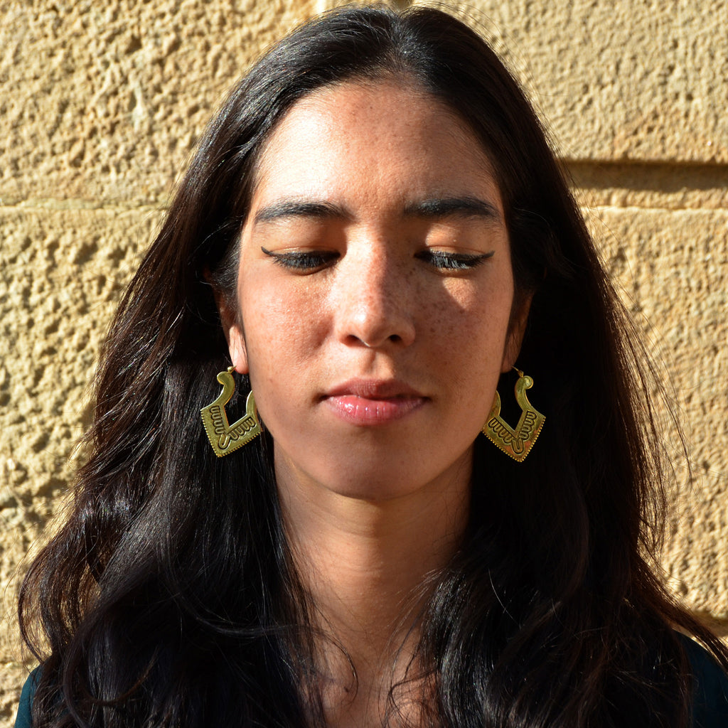 Young woman wearing gold aztec earrings