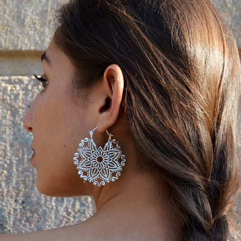 Woman with big silver floral mandala earrings
